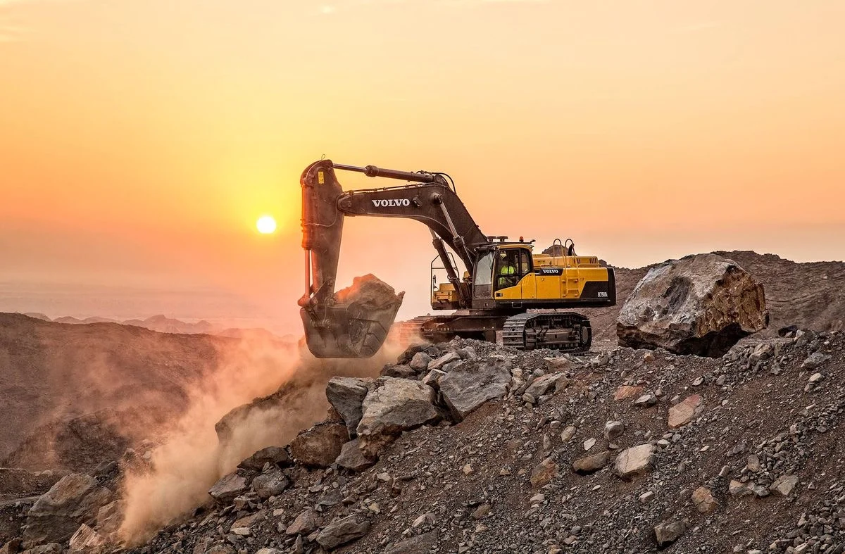 Excavator working a rock face at a surface mine at sunset
